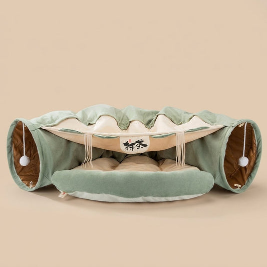 Sage green dual-tunnel cat bed with cream center nest, gold tunnel lining and pom-poms