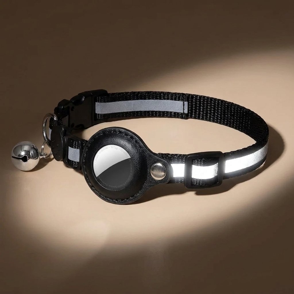 Black AirTag cat collar close-up showing reflective strip, holder, buckle and black bell