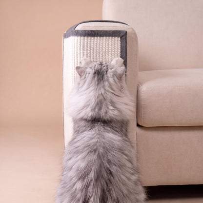 Grey cat from behind using sisal scratch protector on cream sofa arm